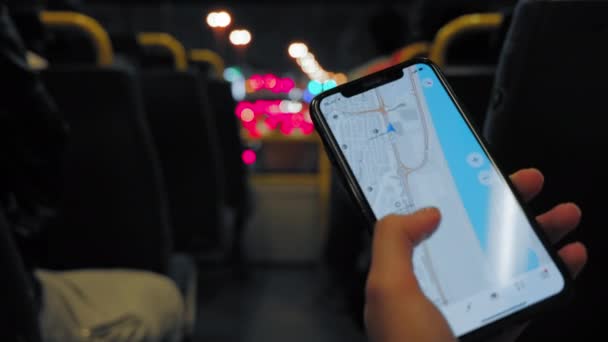 Young unidentified woman uses a GPS navigator on her smartphone while riding a double-decker bus in the UAE dubai. Evening lights of cars and street traffic in the background. — Stock Video