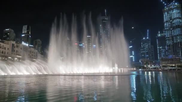 UAE, Dubai - February, 2020: Incredible performance, Dubai musical fountains. Tall skyscrapers and construction cranes in the background. — ストック動画