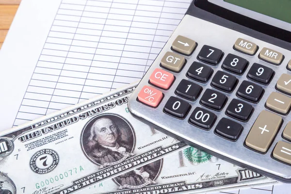 Billetes en dólares y calculadora en papel de informe en blanco —  Fotos de Stock