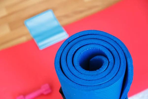 Faixa de borracha com tapete Pilates vermelho na madeira — Fotografia de Stock