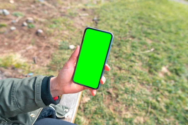 Рука держит зеленый пустой экран телефона с чистым экраном на открытом воздухе — стоковое фото