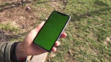 Beyaz beyaz ekran şablonlu akıllı telefonun görüntüsü, kadın el ele tutuşması ve açık havada cep telefonunu gösterme.