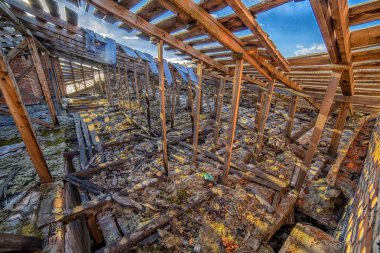 Kırık pencereleri ve kapıları olan büyük, yıkık bir odanın içi.