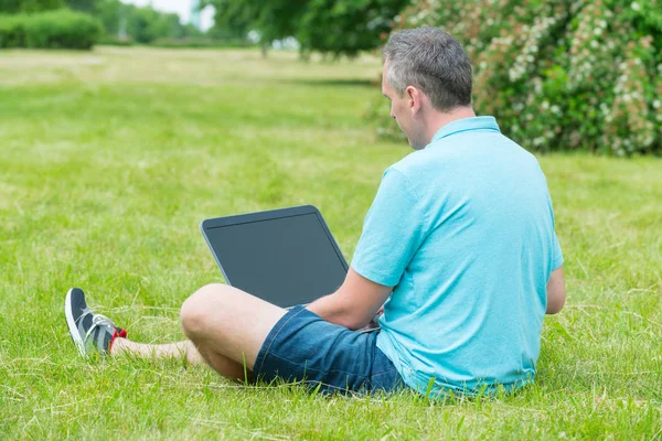 Man werkt aan zijn laptop in het park — Stockfoto