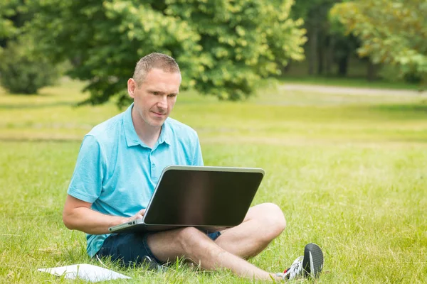 Man working on his laptop in the park — Stock Photo, Image