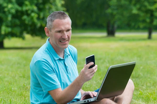 Man werkt aan zijn laptop in het park — Stockfoto