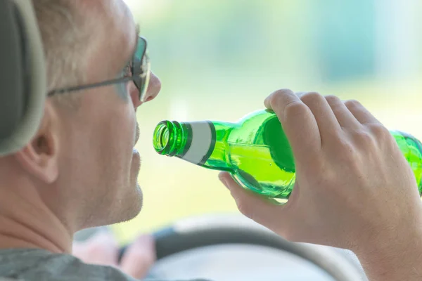 Człowiek pije piwo podczas jazdy samochodem — Zdjęcie stockowe