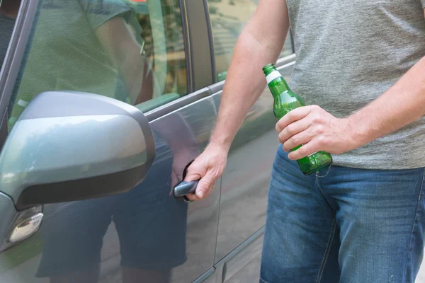 Homme ouvrant sa voiture tout en tenant une bouteille de bière — Photo