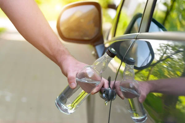 Adam arabasını bir şişe alkol tutarken açma — Stok fotoğraf