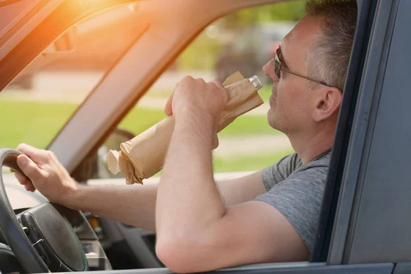 Uomo che beve alcol durante la guida di una macchina — Foto Stock