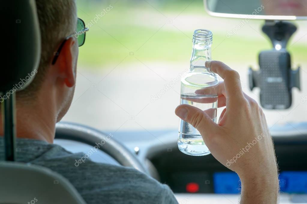 Man drinking alcohol while driving a car