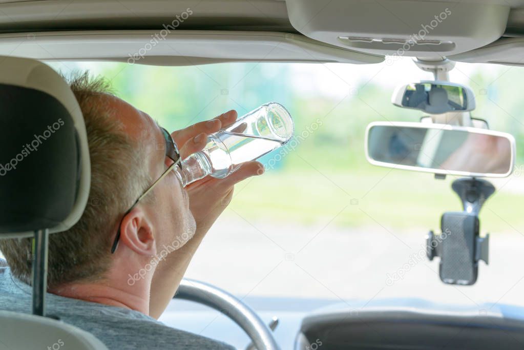 Man drinking alcohol while driving a car