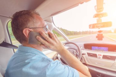 Adam araba kullanırken telefonu kullanıyor.