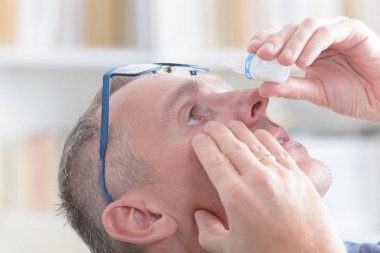 Göz damlası uygulayarak adam