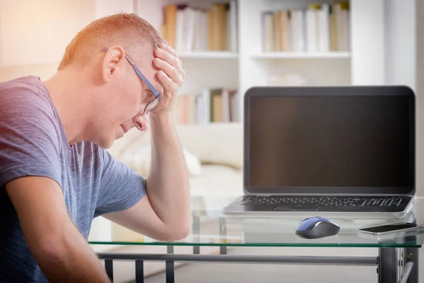 Freelancer hombre en el lugar de trabajo en la oficina sosteniendo la cabeza en las manos —  Fotos de Stock