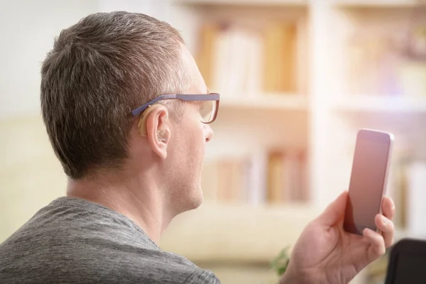 Hearing impaired man working with laptop and mobile phone — Stock Photo, Image