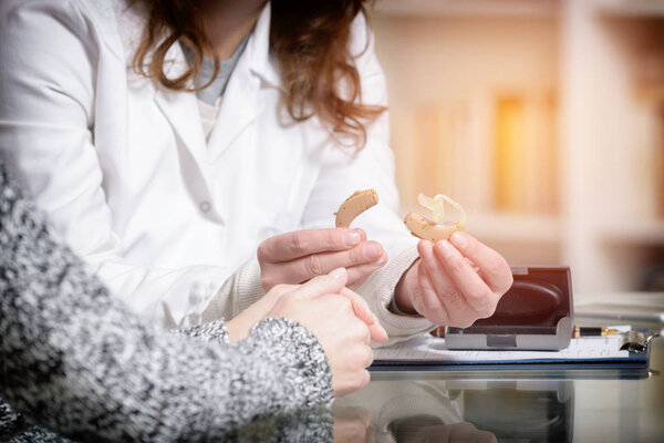 Доктор показывает слуховой аппарат
