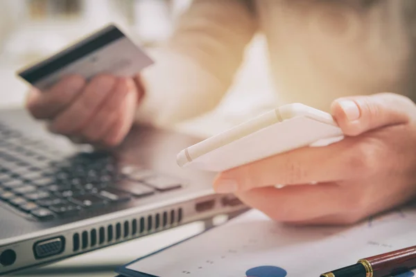 Womans mano celebración de tarjeta de crédito y teléfono inteligente — Foto de Stock