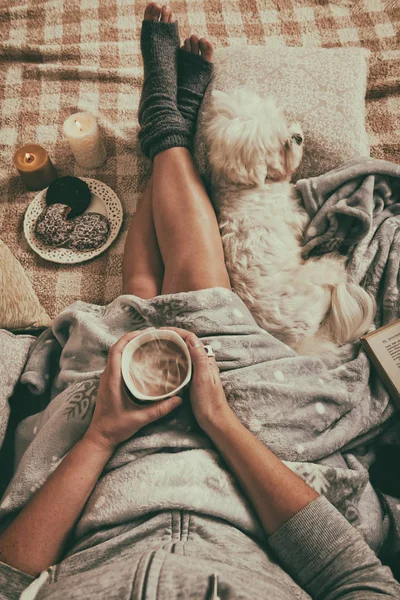 Woman lying on bed with dog — Stock Photo, Image