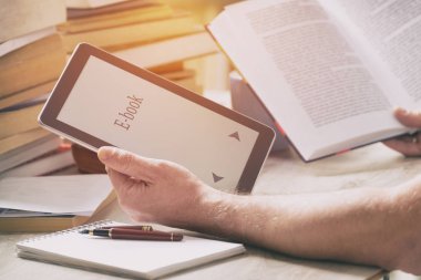 Bir modern ebook okuyucu ve kitap kütüphane içinde tutan adam