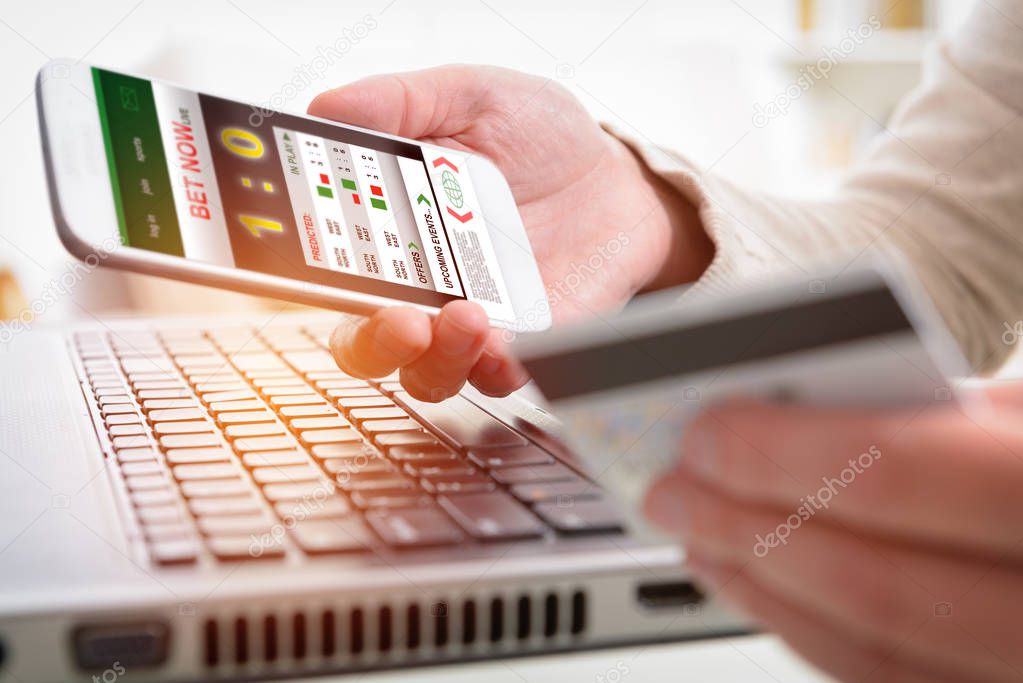 Betting on sports, holding smart phone with working online betting mobile application