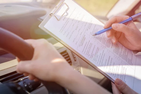 Examinador preenchendo formulário de teste de estrada da carteira de motorista — Fotografia de Stock