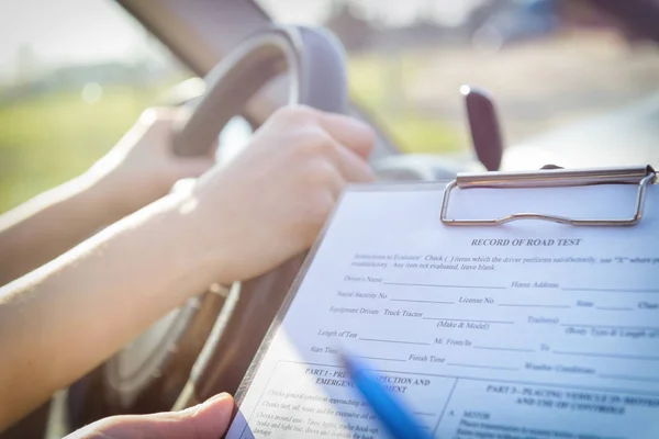 Examinador rellenando el formulario de prueba de la licencia de conducir — Foto de Stock