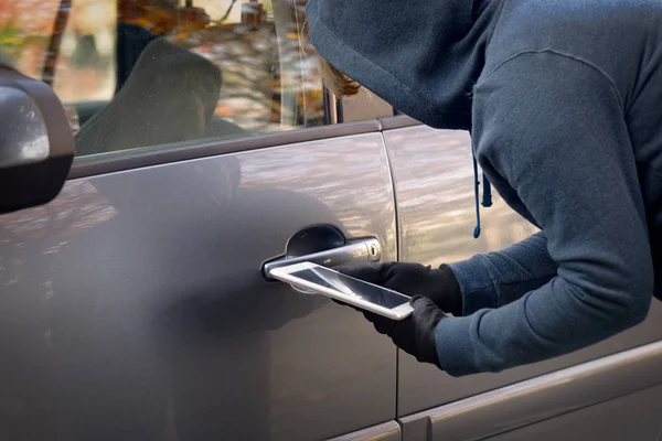 Zakapturzony złodziej próbuje złamać system bezpieczeństwa samochodu tabl — Zdjęcie stockowe
