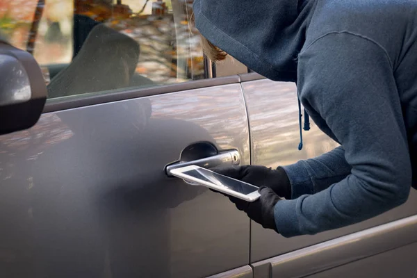 Kapuzendieb versucht Sicherheitssysteme des Autos mit Tablett aufzubrechen — Stockfoto