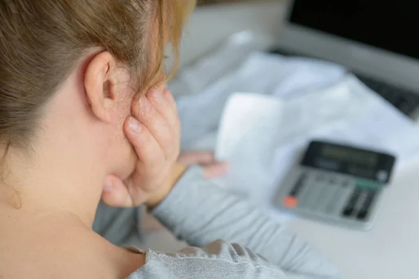 Vrouw gebruikt een rekenmachine om de kosten thuis op te sommen — Stockfoto