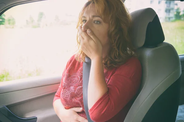 Woman suffering from motion sickness in a car