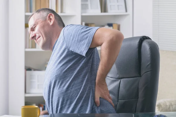 Homem Escritório Casa Sofrendo Dor Lombar Sentado Uma Mesa Com — Fotografia de Stock