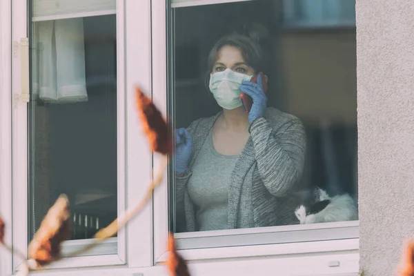 Woman Using Smartphone Wearing Protective Face Mask Looking Out Window — Stock Photo, Image