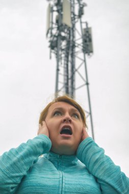 Kadın kafasını BTS 'nin yakınında tutuyor. Hücresel 5G ağ ileticileri kavramından zararlı radyasyon