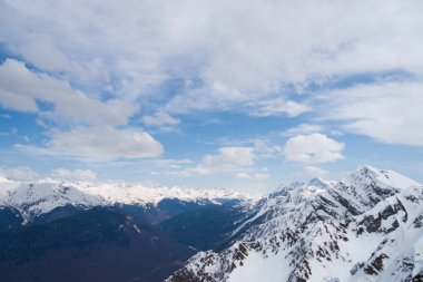Karla kaplı dağların zirveleri Bulutlu mavi gökyüzüne karşı