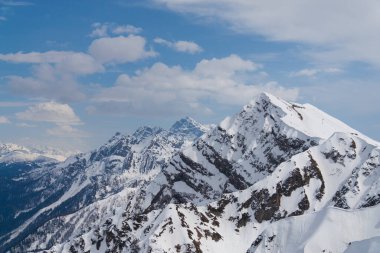 Karla kaplı dağların zirveleri Bulutlu mavi gökyüzüne karşı