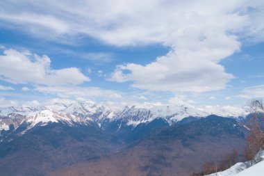 Karla kaplı dağların zirveleri Bulutlu mavi gökyüzüne karşı