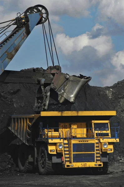 Schwerer Bagger lädt Kohle in einem Kohlebergwerk in einen Schwertransporter — Stockfoto