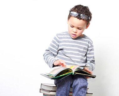 Okul kitaplarıyla beyaz arka planı olan küçük bir çocuk. 