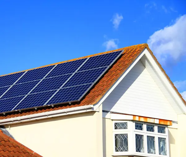 solar panels on house roof top with blue sky and sun generating electrical power for the customer