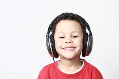 Müzik dinleyen şirin, melez bir çocuğun portresi.