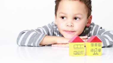 Mülk alımını temsil eden minyatür oyuncak blok evleriyle oynayan küçük çocuk.
