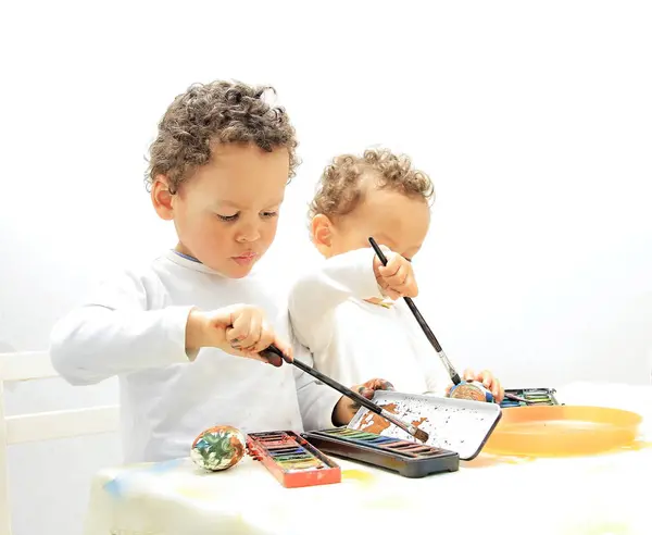 Easter eggs with boys decorating and painting the eggs with white background