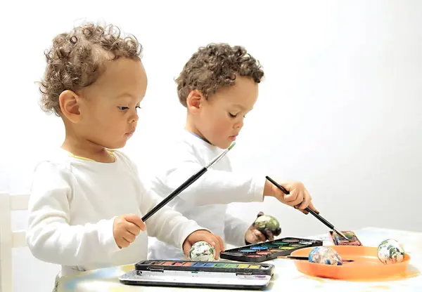 Easter eggs with boys decorating and painting the eggs with white background