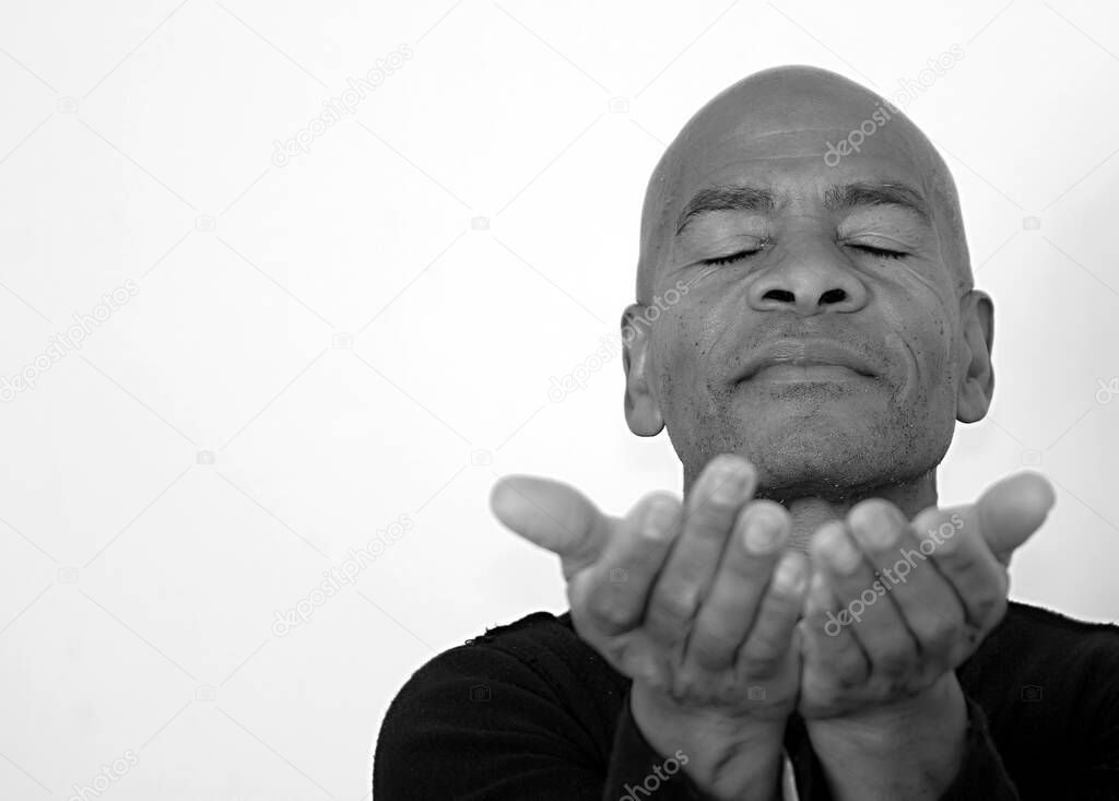 man praying to god with hands together Caribbean man praying with white background stock photo