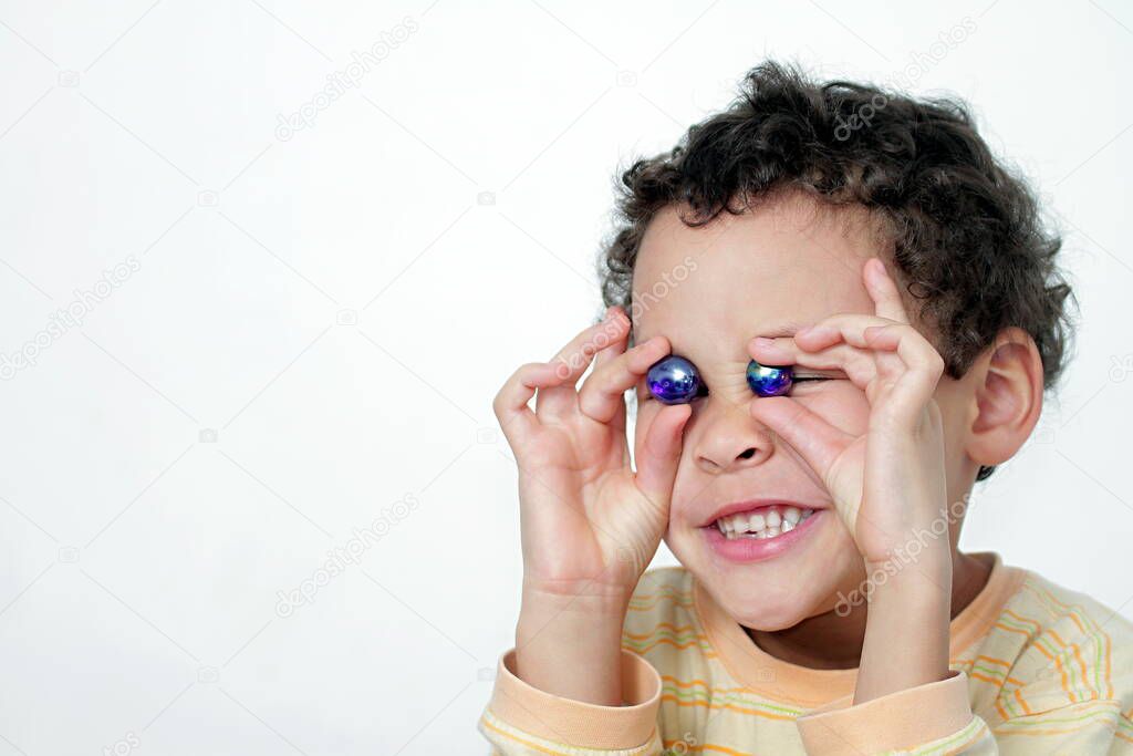 little boy looking through his toy marble with white background 