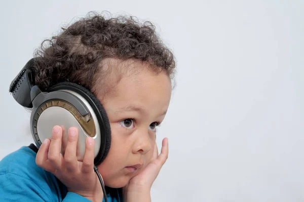 Kulaklıklı çocuk beyaz arka planda müzik dinliyor.