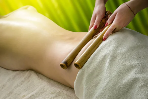 Masseur doing massage with bamboo sticks