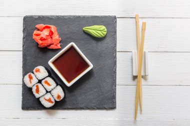 Beyaz arka planda taş bir tabakta suşi.