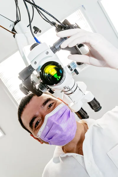 Dentist with a microscope in a dental clinic. Doctor holding a microscope view from below